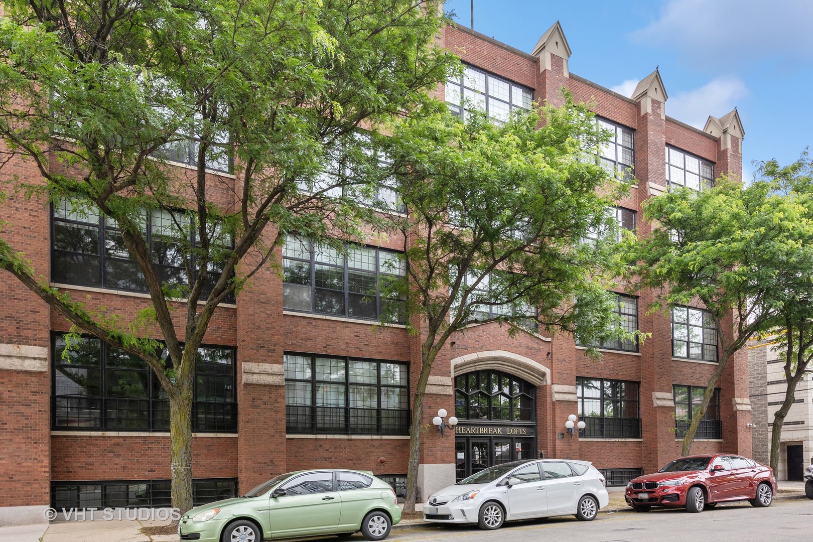 a front view of a building with cars parked