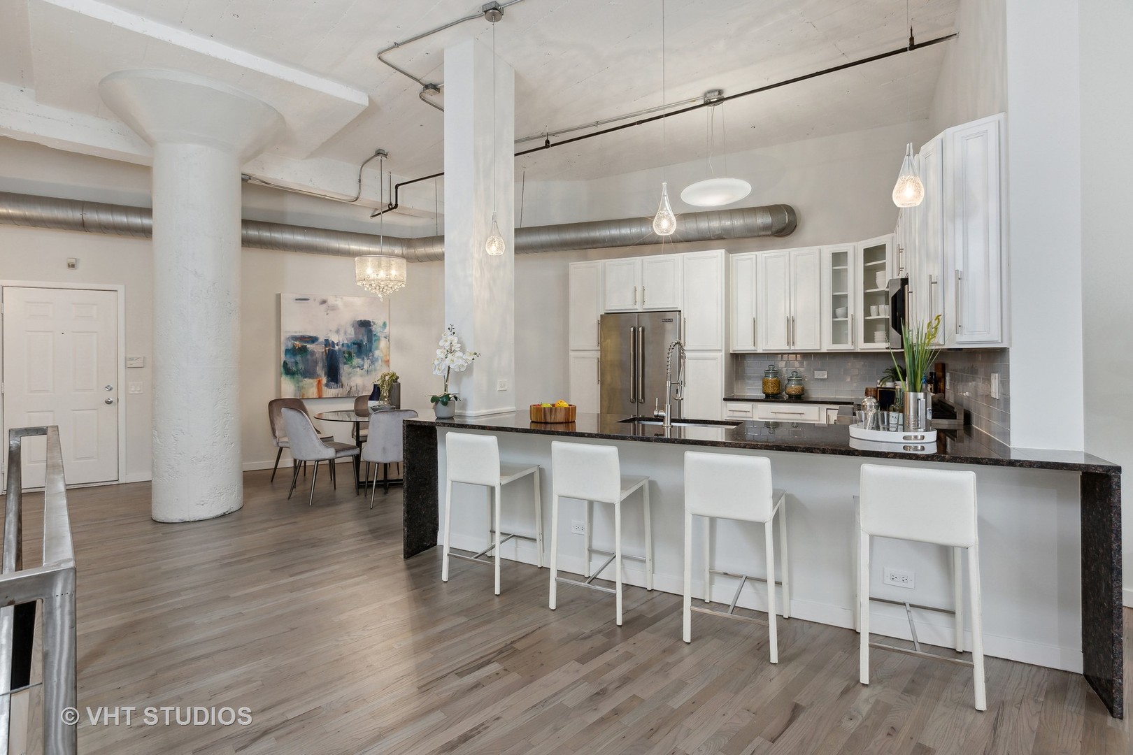 17 North Loomis Street, Unit 1J Chicago, IL 60607 - Photo 7 of 30 a kitchen with stainless steel appliances a table chairs refrigerator and microwave