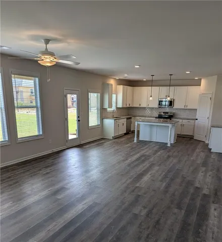 an open kitchen with kitchen island wooden floors appliances and cabinets