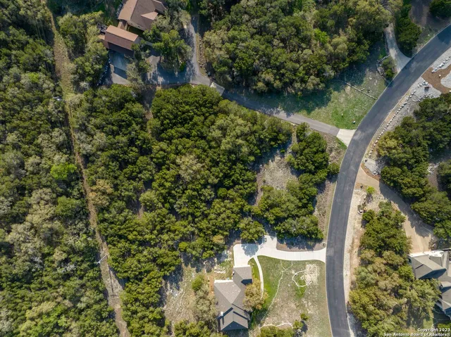 an aerial view of residential house with outdoor space and trees all around