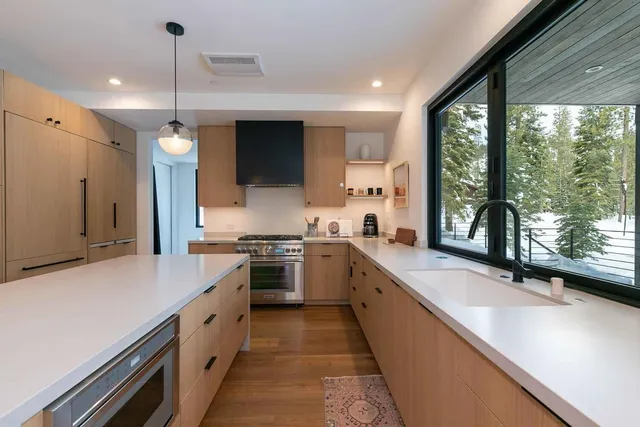 a large kitchen with stainless steel appliances a large counter top a stove a sink and a refrigerator