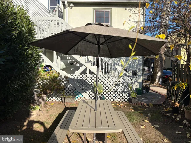 a backyard of a house with table and chairs under an umbrella