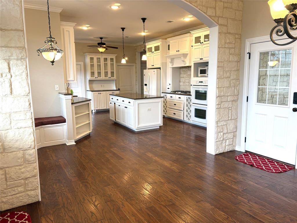 1170 Brazos Loop Gholson, TX 76705 - Photo 16 of 37 Spacious kitchen featuring an expansive center island, white cabinetry, built-in double ovens, and wood-finish flooring