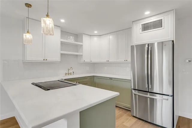 a kitchen that has a refrigerator a sink and white cabinets