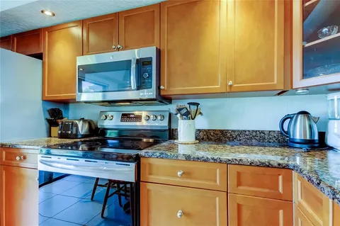 a kitchen with granite countertop a stove a sink and a microwave