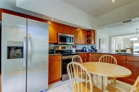 a kitchen with stainless steel appliances granite countertop a refrigerator a stove a sink a dining table and chairs