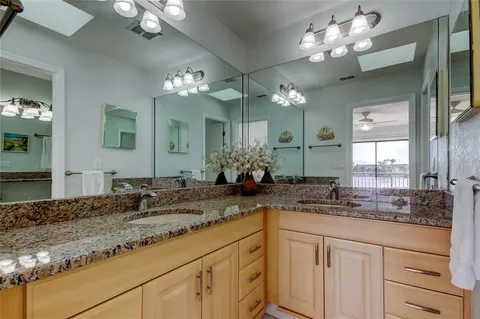 a bathroom with a granite countertop sink a toilet a mirror and shower