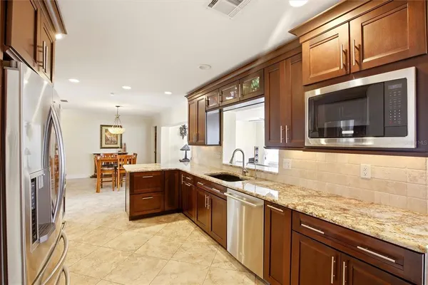 a kitchen with stainless steel appliances granite countertop sink stove refrigerator and cabinets