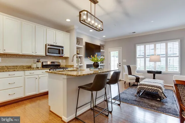 a kitchen with stainless steel appliances granite countertop a stove top oven a sink dishwasher a dining table and chairs with wooden floor