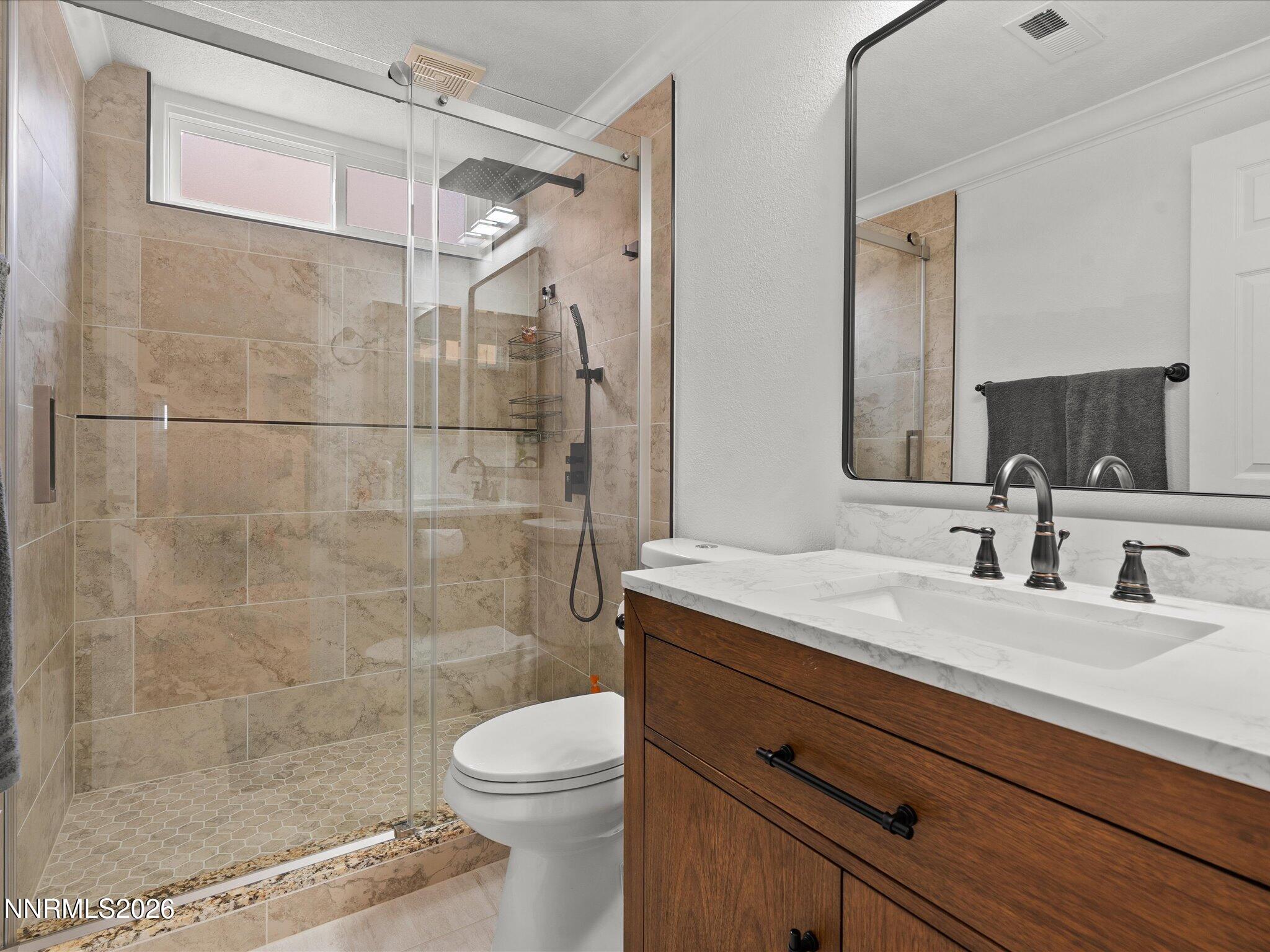 4943 Foxcreek Trail Reno, NV 89519 - Photo 15 of 26 a bathroom with a granite countertop sink a toilet a mirror and shower