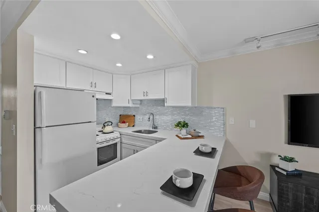 a kitchen with a refrigerator a stove a sink and a dining table with chairs