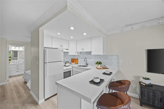 a kitchen with a refrigerator a stove and wooden floor