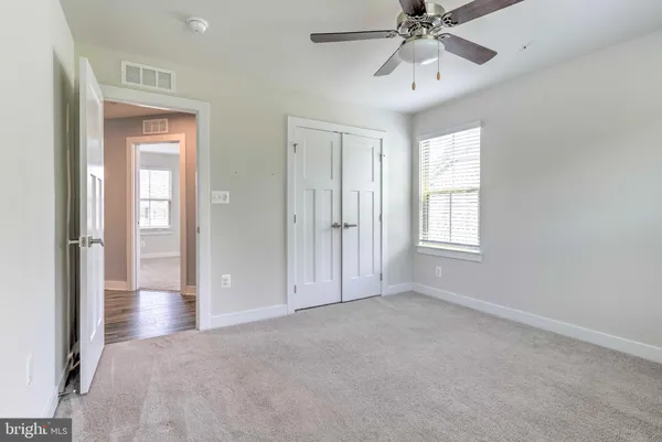 a view of an empty room with chandelier fan and fire place