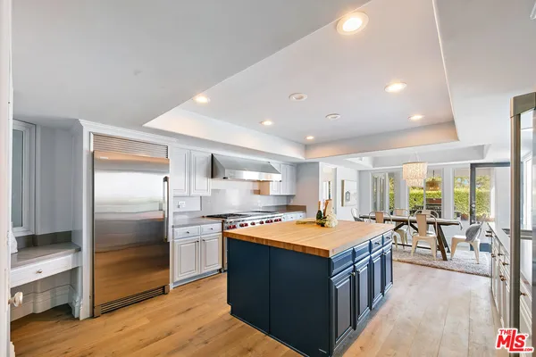 a kitchen with stainless steel appliances granite countertop a refrigerator a sink dishwasher a stove and a dining table with wooden floor