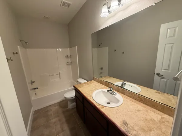 a bathroom with a granite countertop sink a toilet a mirror and shower