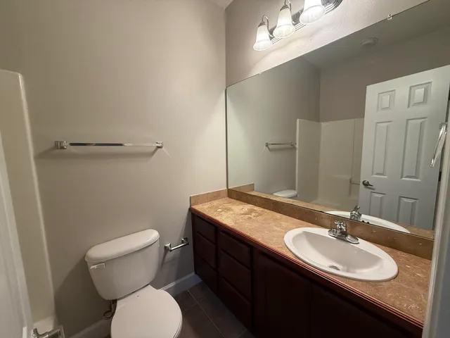 a bathroom with a granite countertop toilet a sink and a mirror