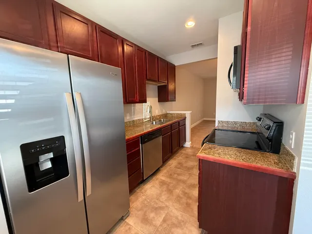 a kitchen with stainless steel appliances granite countertop a refrigerator a stove a sink and a microwave