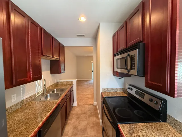 a kitchen with stainless steel appliances granite countertop a stove a sink and a microwave
