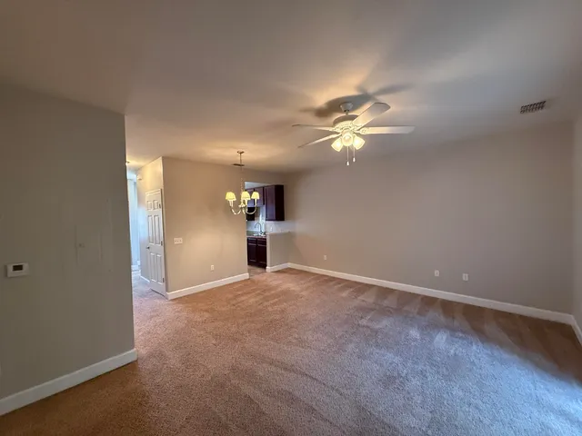 an empty room with chandelier fan and windows