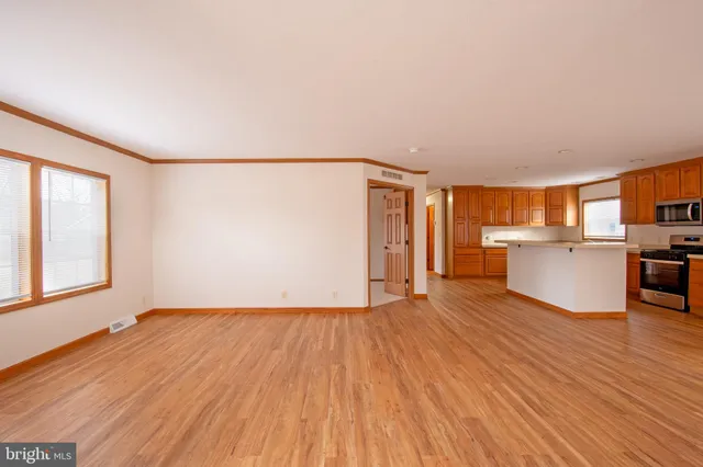 a view of a big room with wooden floor and windows