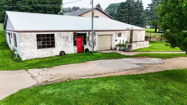 a view of a white house next to a yard and large trees