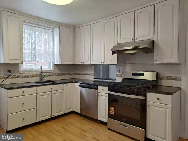 a kitchen with granite countertop wooden cabinets and a stove