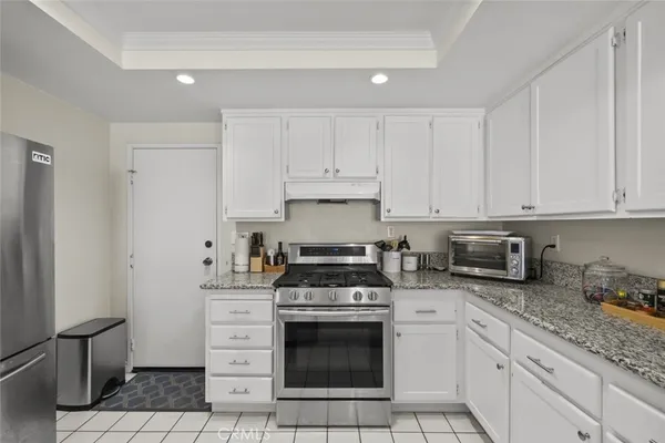 a kitchen with granite countertop white cabinets and stainless steel appliances