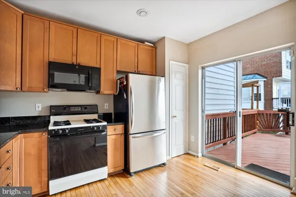 a kitchen with granite countertop wooden floors stainless steel appliances and a sink