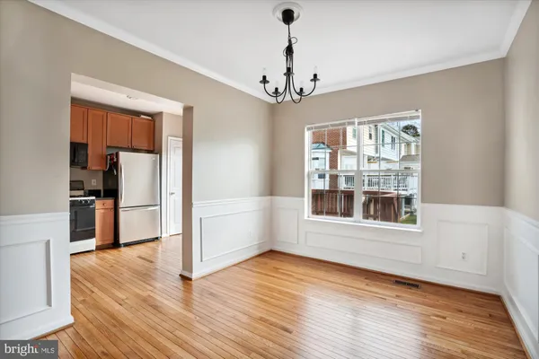 a view of a room with wooden floor chandelier and windows