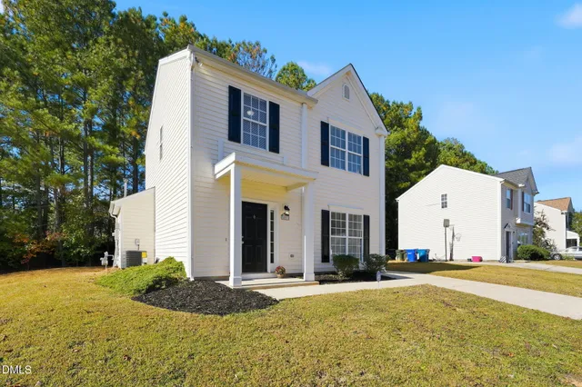 a view of a white house with a yard and plants
