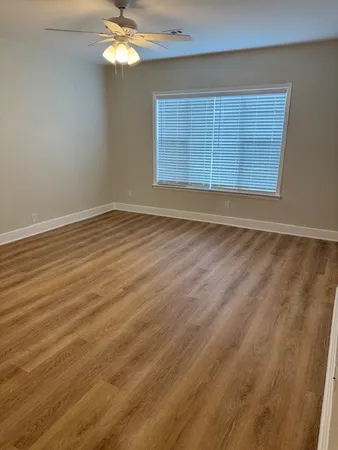 a view of an empty room with wooden floor and a window