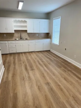 a view of an empty room with kitchen and window