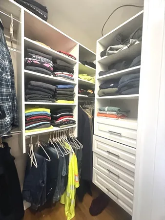 a view of walk in closet with clothes and shoes