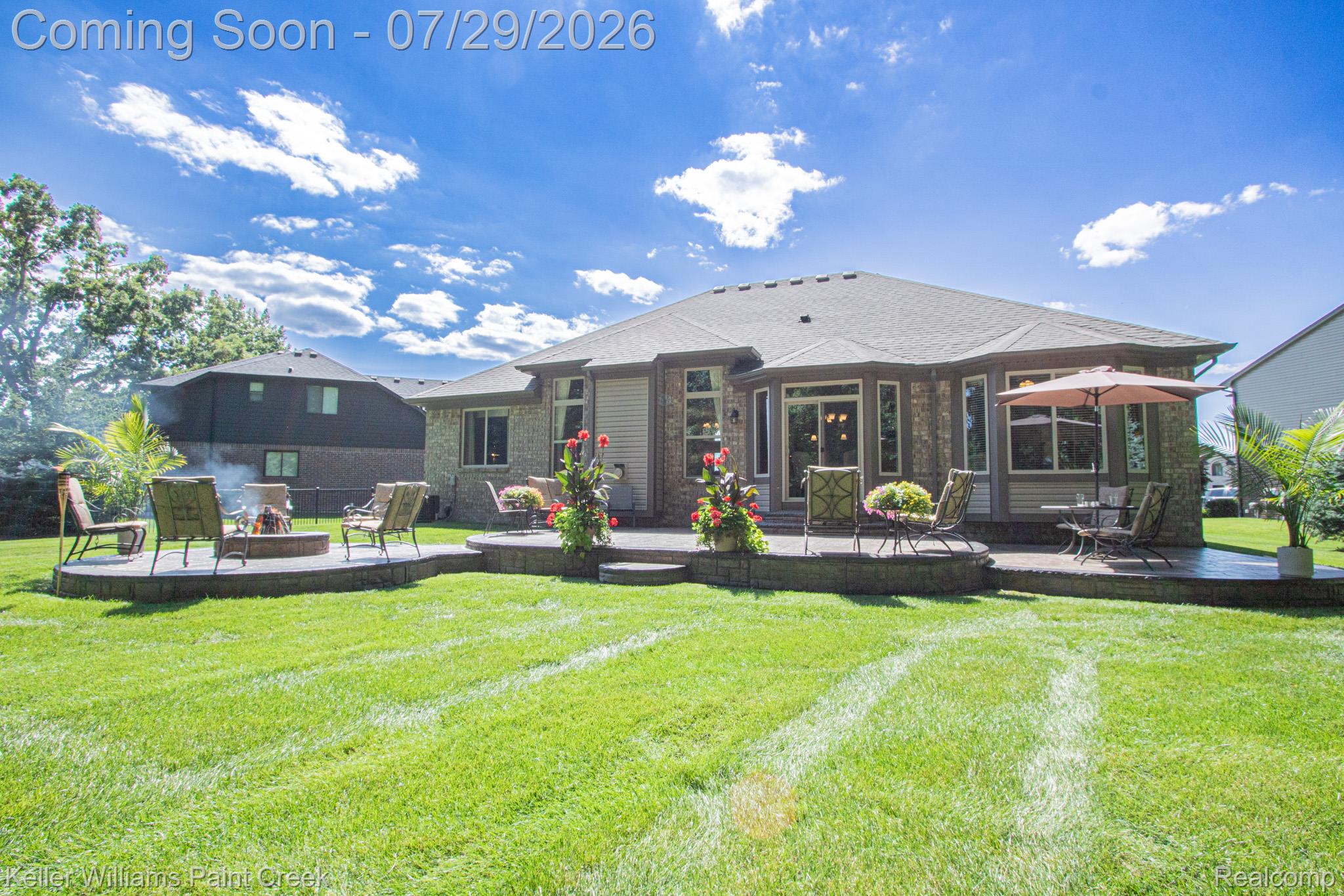 49118 Ridgeview Drive Macomb, MI 48044 - Photo 50 of 57 Expansive green lawn with a multi-level paver patio featuring a built-in fire pit and a raised dining area