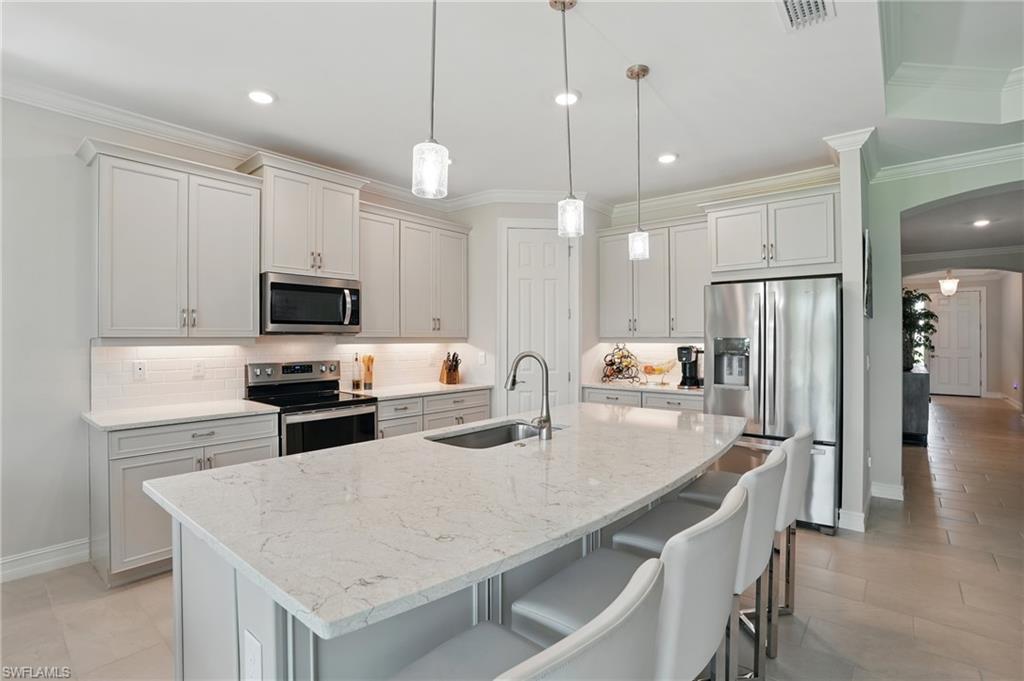 28165 Captiva Shell Loop Bonita Springs, FL 34135 - Photo 11 of 38 a kitchen with stainless steel appliances granite countertop a table chairs stove microwave and refrigerator