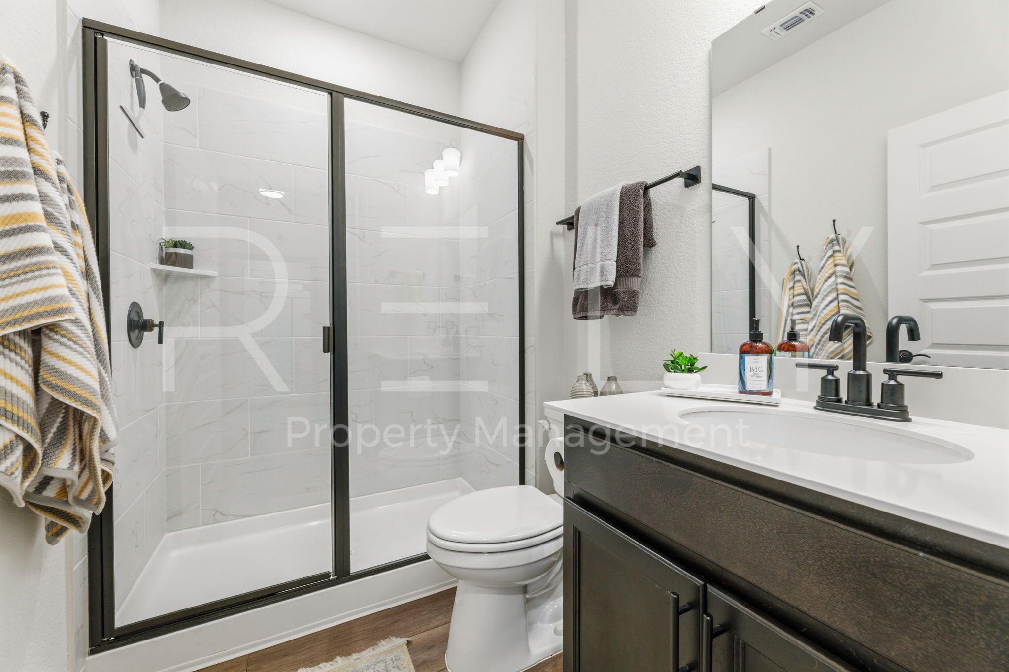101 Spanish Star Street Georgetown, TX 78633 - Photo 29 of 39 A well-appointed bathroom features a modern vanity and a tiled walk-in shower with a sleek glass enclosure.