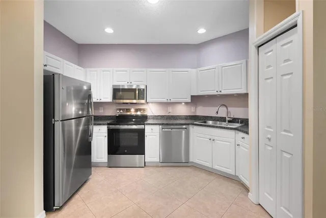 a kitchen with stainless steel appliances granite countertop a refrigerator a stove a sink and a microwave