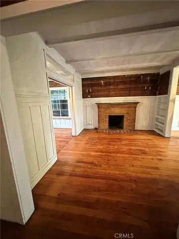 a view of empty room with wooden floor and fireplace