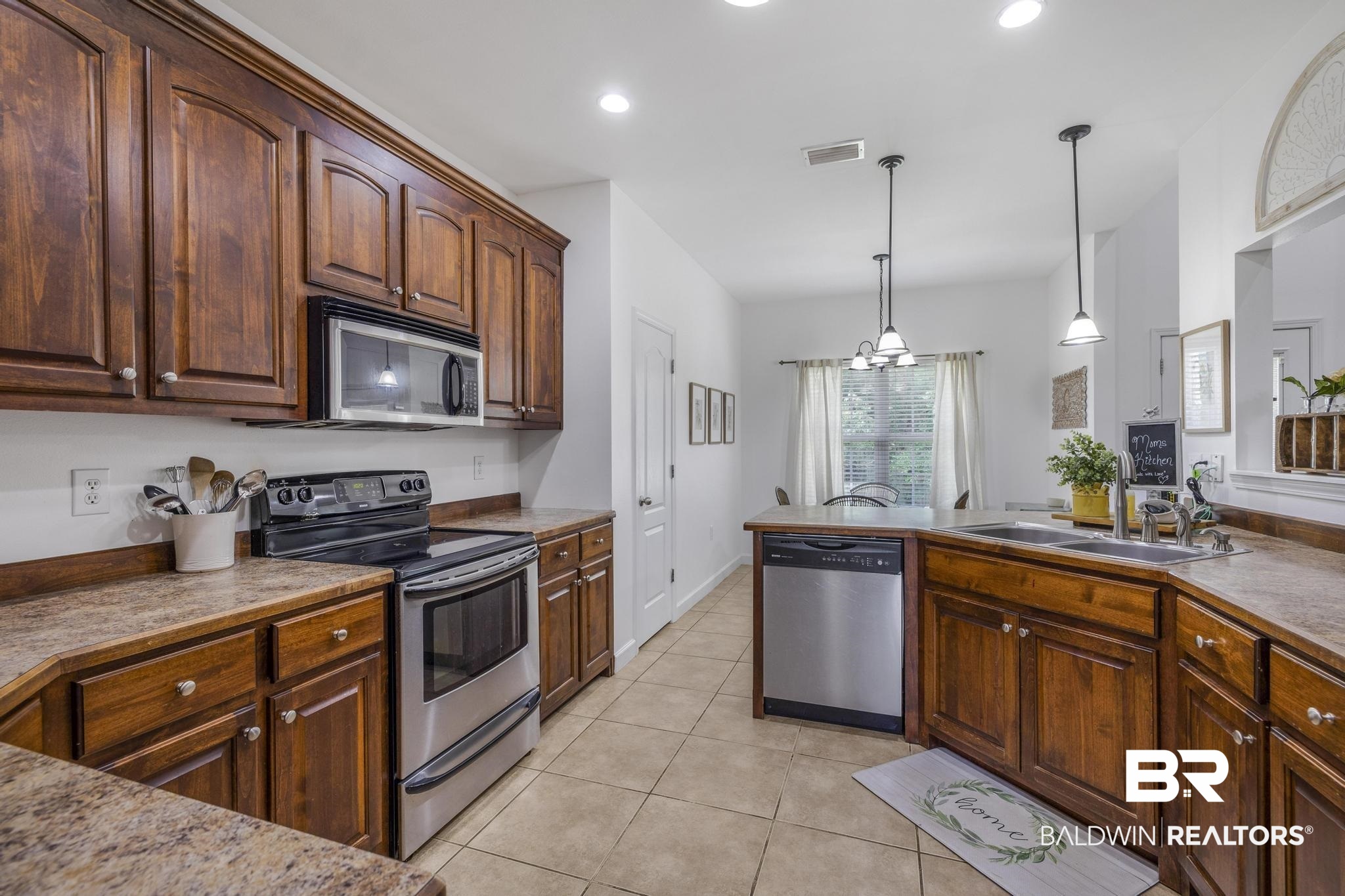 35814 Delvan Lane Bay Minette, AL 36507 - Photo 15 of 53 Kitchen featuring wood cabinetry, stainless steel appliances, speckled countertops, and tile flooring