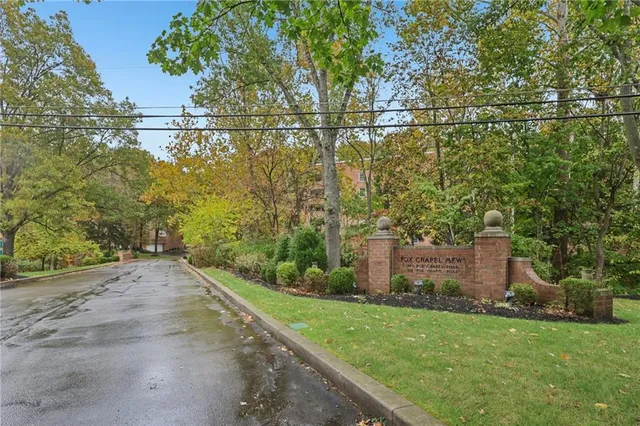 a front view of a building with trees and sitting area