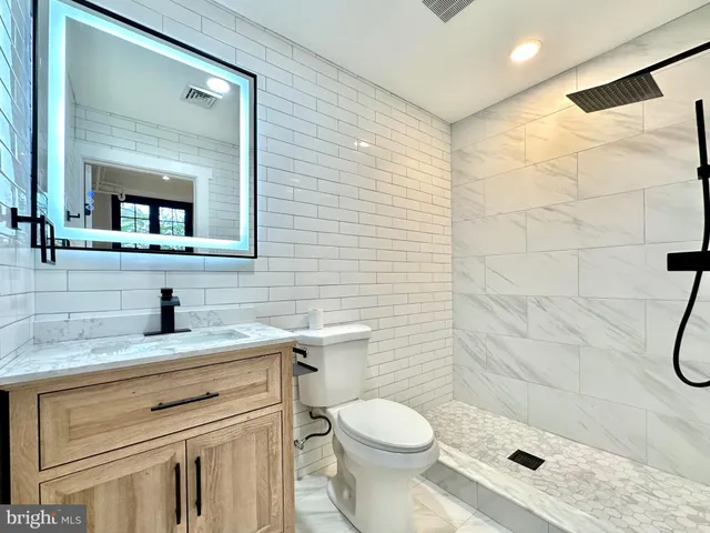 a bathroom with a granite countertop sink a toilet and a mirror