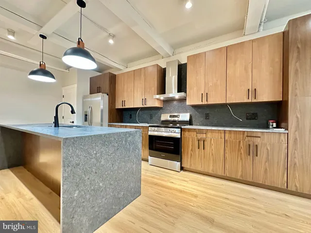 a kitchen with stainless steel appliances granite countertop a sink a stove and a refrigerator