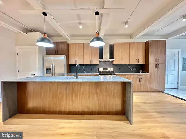 a kitchen with stainless steel appliances granite countertop a refrigerator a sink dishwasher a stove and white cabinets with wooden floor