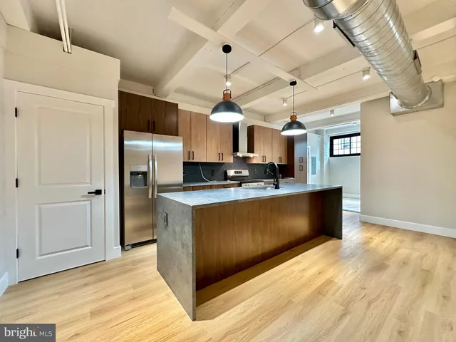 a kitchen with stainless steel appliances granite countertop a refrigerator a sink dishwasher a oven and a dining table with wooden floor