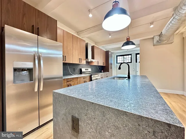a kitchen with stainless steel appliances granite countertop a refrigerator a stove and a sink with granite countertops
