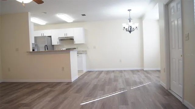 an empty room with wooden floor and kitchen view