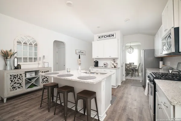 a kitchen with stainless steel appliances granite countertop a stove a sink dishwasher and cabinets with wooden floor