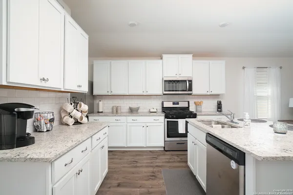 a kitchen with a sink white cabinets and white appliances