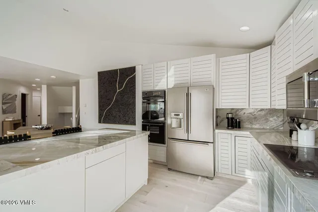a kitchen with stainless steel appliances granite countertop a sink and a refrigerator