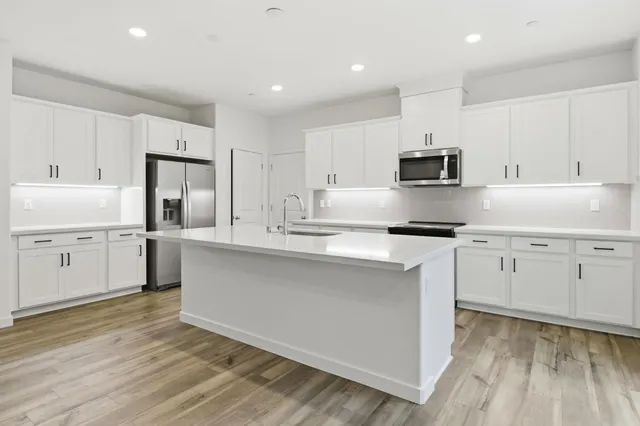 a kitchen with white cabinets and appliances